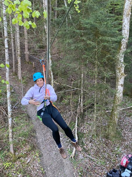 Zipline Allgäu Aufstieg zum Flying Fox Eine Frau hangelt sich an einen Stahlseil Aufstieg mit Klettergurt beim Zipline Allgü entlang